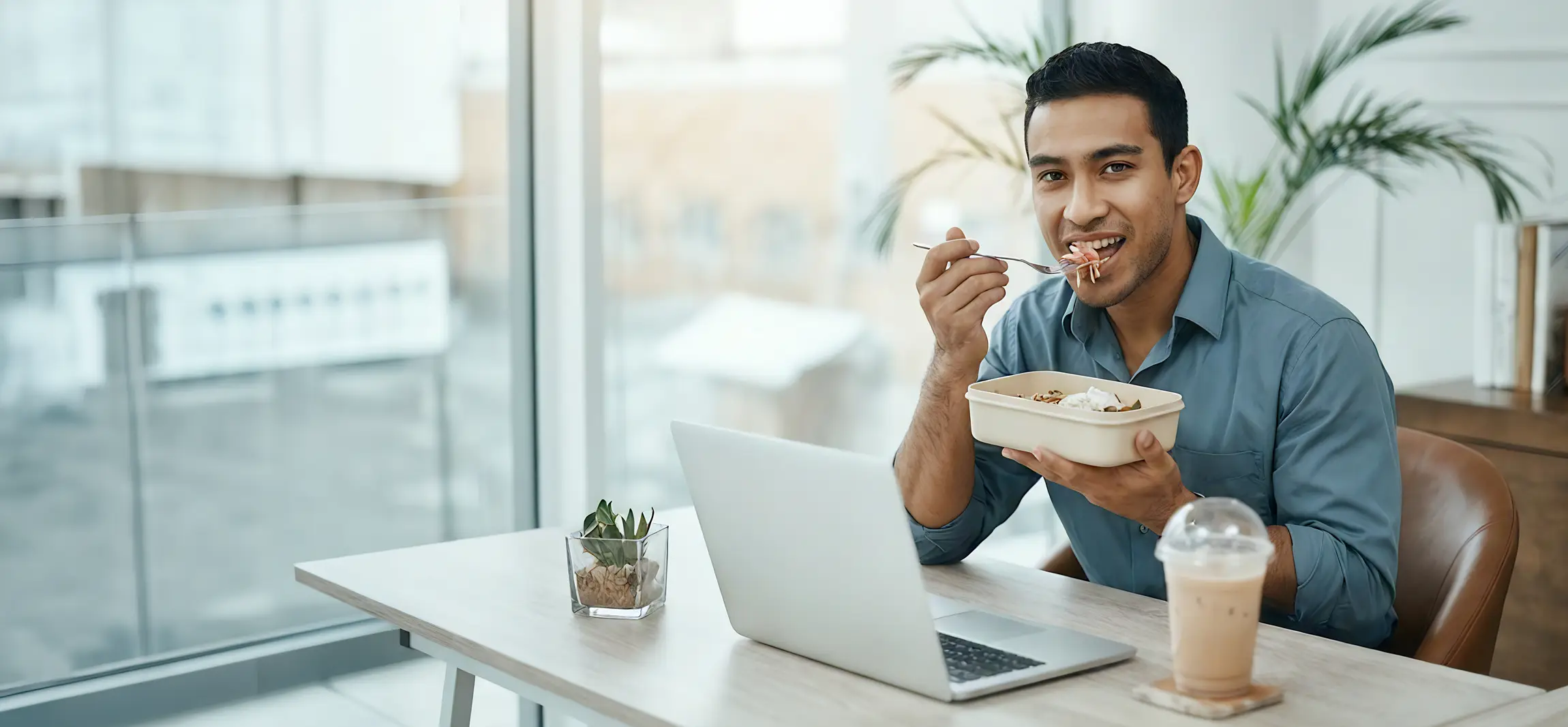A social worker working at his desk, eating his lunch.