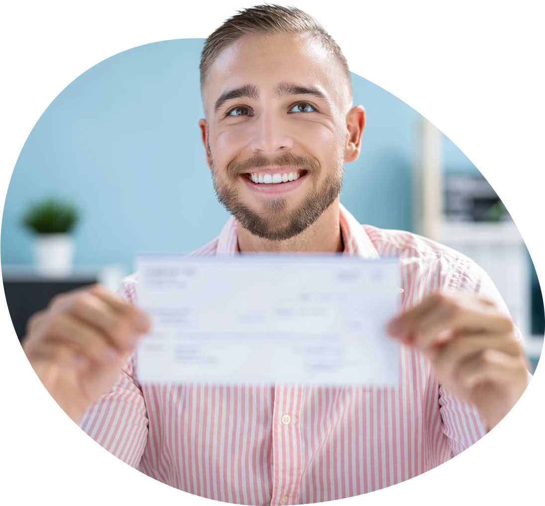 A man holding a check in his hand with a big smile