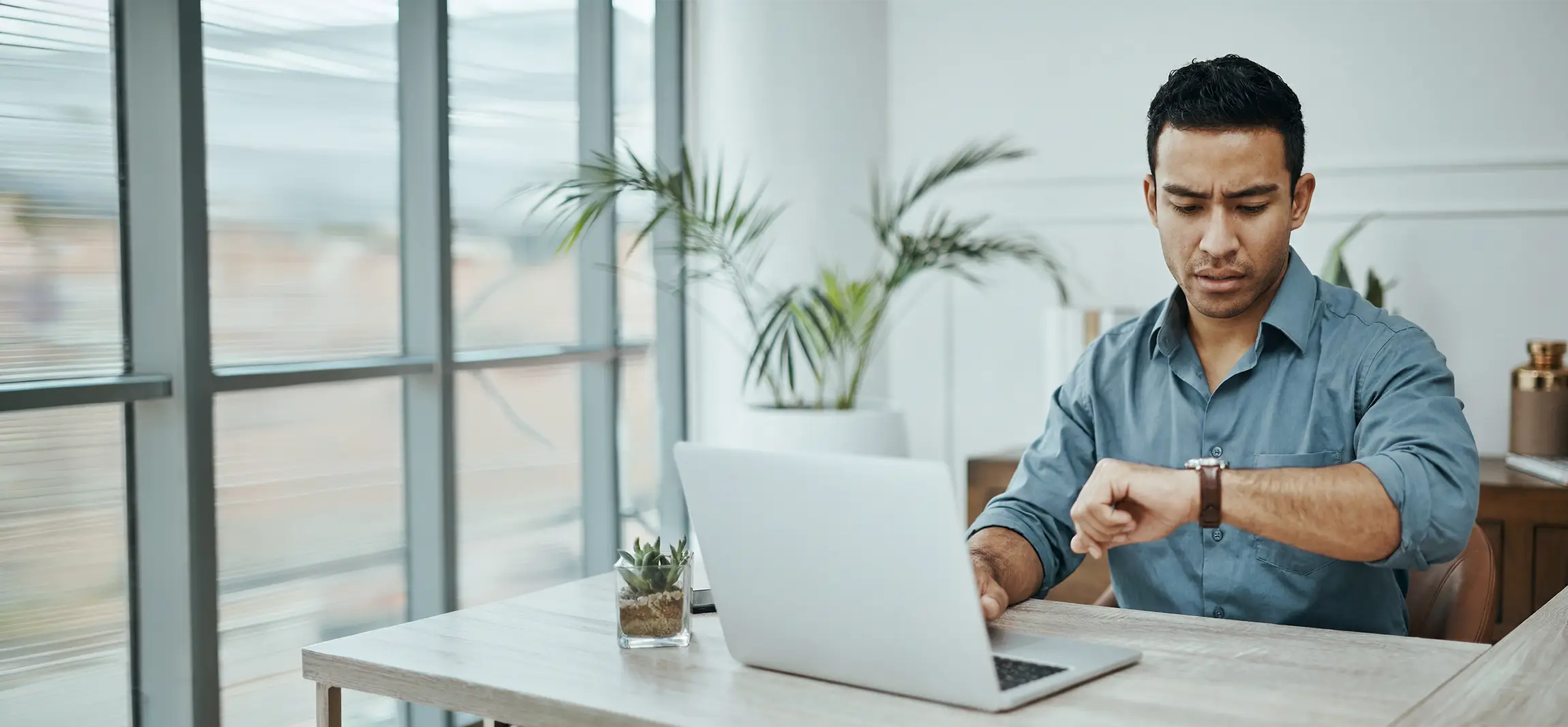 A social worker working at his desk and checking his watch to see how late he should work.