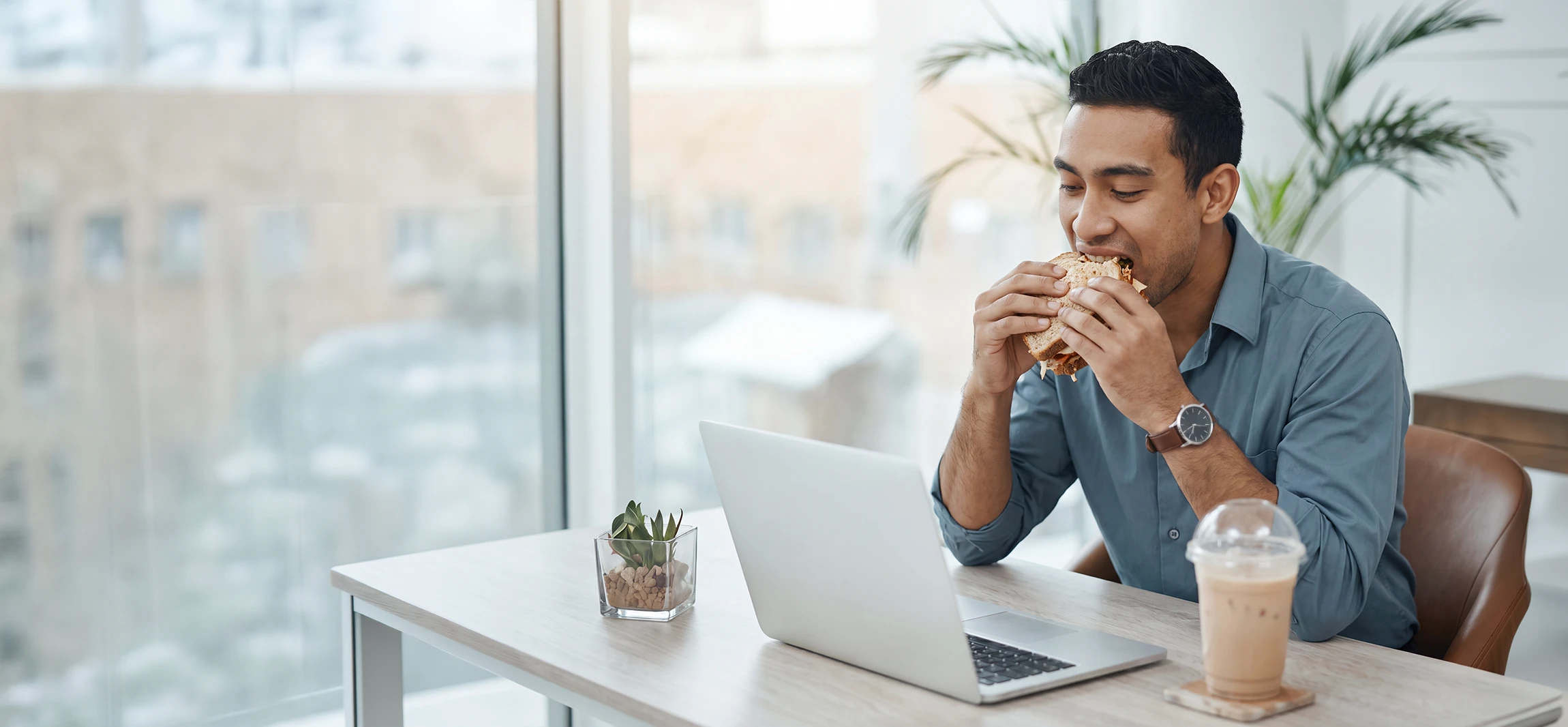 A social worker working at his desk, eating his lunch.